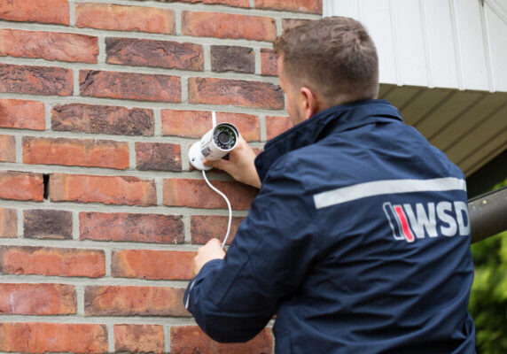 WSD Sicherheitsmitarbeiter installiert Überwachungskamera an Hauswand zur Einbruchprävention